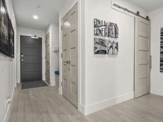 Step into this inviting hallway featuring a sleek dark gray front door with a digital lock, leading into a well-lit space.