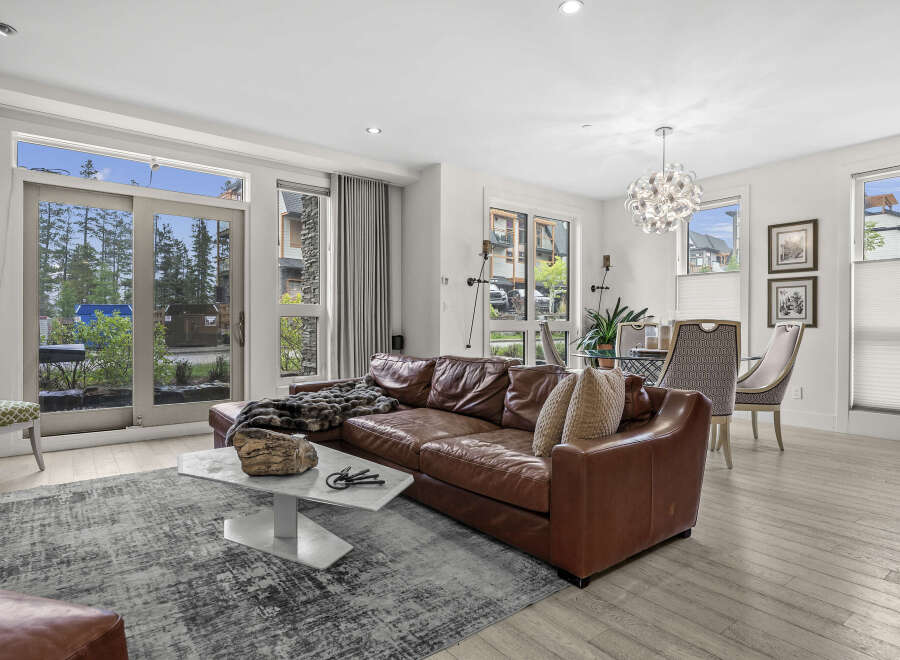 Experience modern living in this spacious condo featuring a luxurious brown leather sectional sofa and a striking marble coffee table.