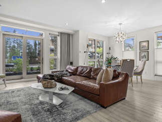 Experience modern living in this spacious condo featuring a luxurious brown leather sectional sofa and a striking marble coffee table.