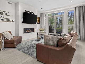 Experience modern mountain living in this stunning living room, featuring a sleek gas fireplace and a large flat-screen TV mounted above.
