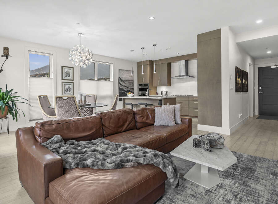Experience modern living in this stunning open-concept condo, featuring a spacious living area with a luxurious leather sectional and a sleek, contemporary kitchen perfect for entertaining.