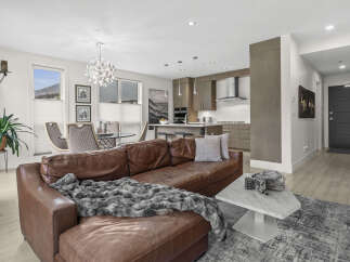 Experience modern living in this stunning open-concept condo, featuring a spacious living area with a luxurious leather sectional and a sleek, contemporary kitchen perfect for entertaining.