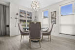This dining area features a stylish chandelier and elegant upholstered chairs surrounding a glass-top dining table.