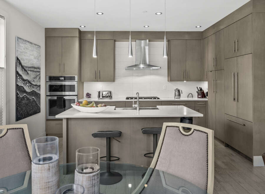 Experience modern luxury in this stunning kitchen, featuring sleek, taupe cabinetry and a spacious quartz island perfect for entertaining.