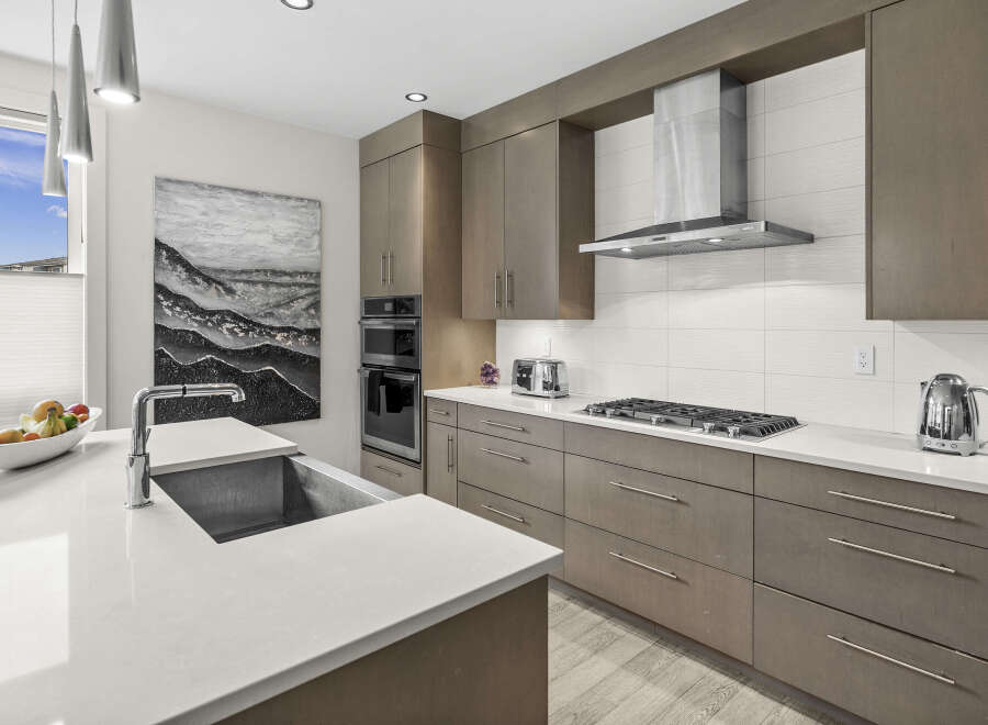 Experience modern luxury in this stunning kitchen, featuring sleek, grey cabinetry and a spacious quartz countertop.