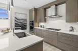 Experience modern luxury in this stunning kitchen, featuring sleek, grey cabinetry and a spacious quartz countertop.