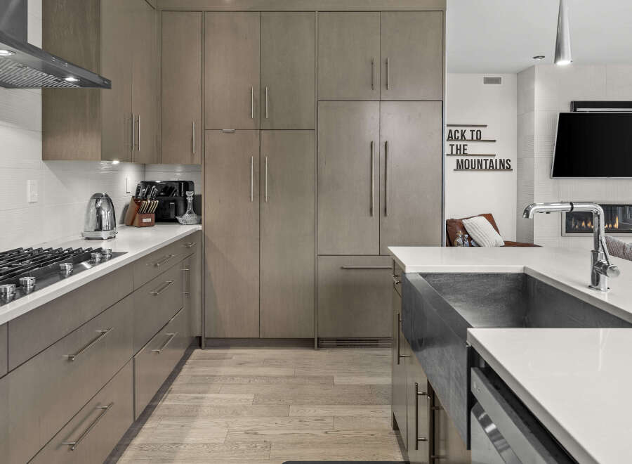 Experience modern luxury in this stunning kitchen, featuring sleek, taupe cabinetry and a spacious quartz countertop.