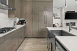 Experience modern luxury in this stunning kitchen, featuring sleek, taupe cabinetry and a spacious quartz countertop.