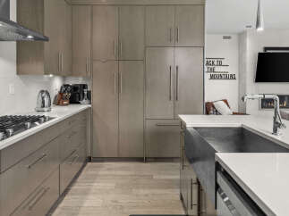 Experience modern luxury in this stunning kitchen, featuring sleek, taupe cabinetry and a spacious quartz countertop.