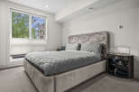 Experience modern comfort in this stylish bedroom, featuring a plush, upholstered bed with a unique geometric headboard and coordinating grey bedding.
