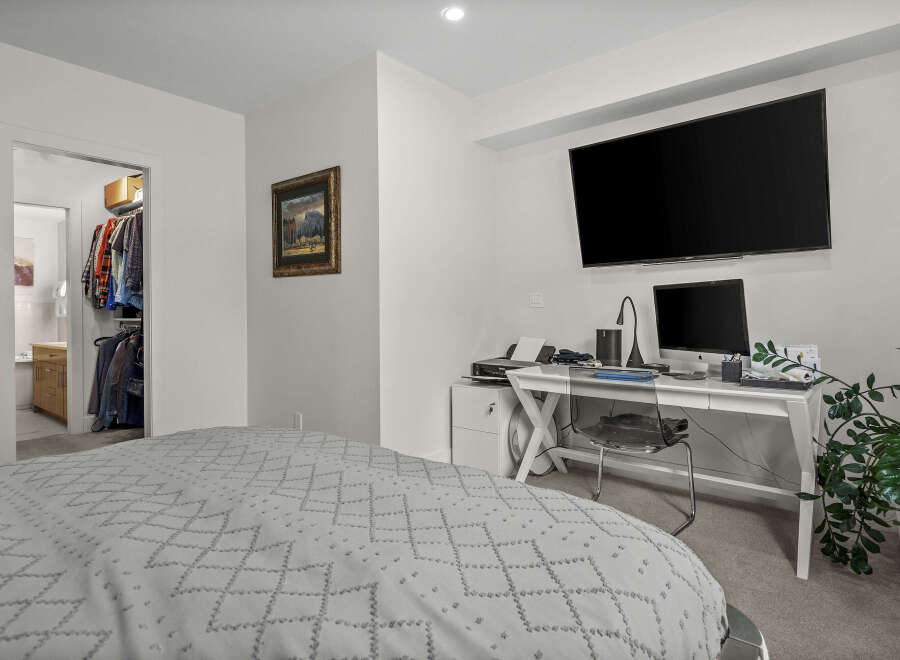 This bedroom offers a comfortable and functional space, featuring a large bed with a patterned duvet and a convenient walk-in closet.