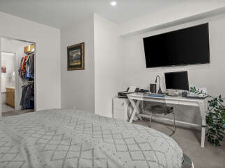 This bedroom offers a comfortable and functional space, featuring a large bed with a patterned duvet and a convenient walk-in closet.