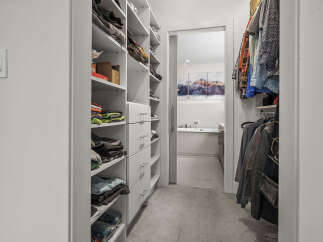Step into this spacious walk-in closet, featuring ample shelving and drawers for organized storage.