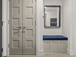 Step into a welcoming entryway featuring a stylish bench with a plush blue cushion, perfect for putting on shoes.