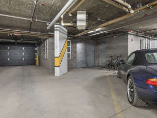 Discover secure and convenient parking in this spacious garage, featuring a sleek black overhead door and ample room for your vehicles.