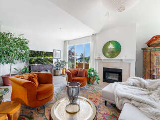 Experience luxurious living in this stunning living room, featuring plush velvet armchairs and a cozy fireplace.