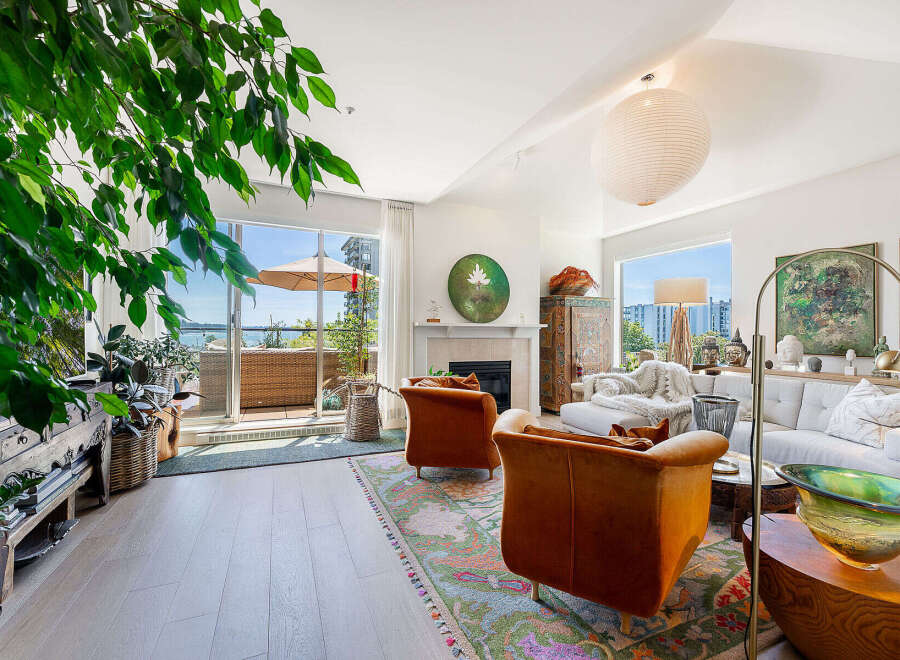 Experience luxurious living in this stunning apartment, featuring a spacious living area with a cozy fireplace and large windows that open to a private balcony with water views.