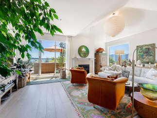 Experience luxurious living in this stunning apartment, featuring a spacious living area with a cozy fireplace and large windows that open to a private balcony with water views.