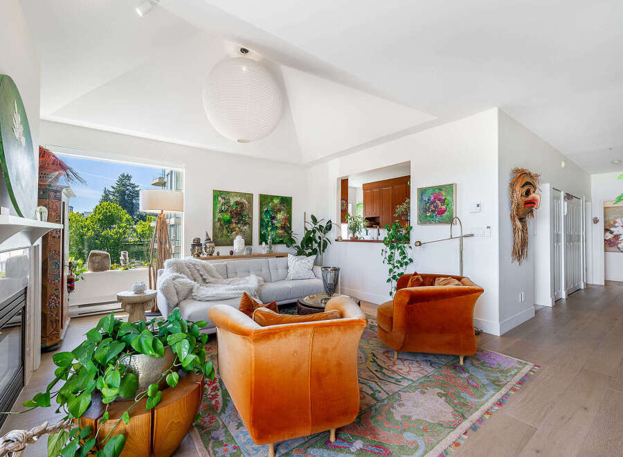 Experience sophisticated living in this stunning living room, featuring a plush grey sofa adorned with a cozy throw, complemented by two vibrant orange accent chairs.