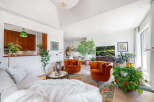Experience modern living in this stylish living room, featuring plush orange velvet armchairs and a comfortable white sofa adorned with a faux fur throw.