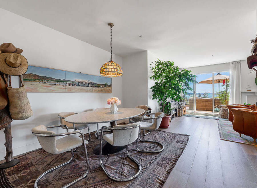 Experience coastal living in this stunning dining area, featuring a marble-topped oval table surrounded by chic chrome-accented chairs.