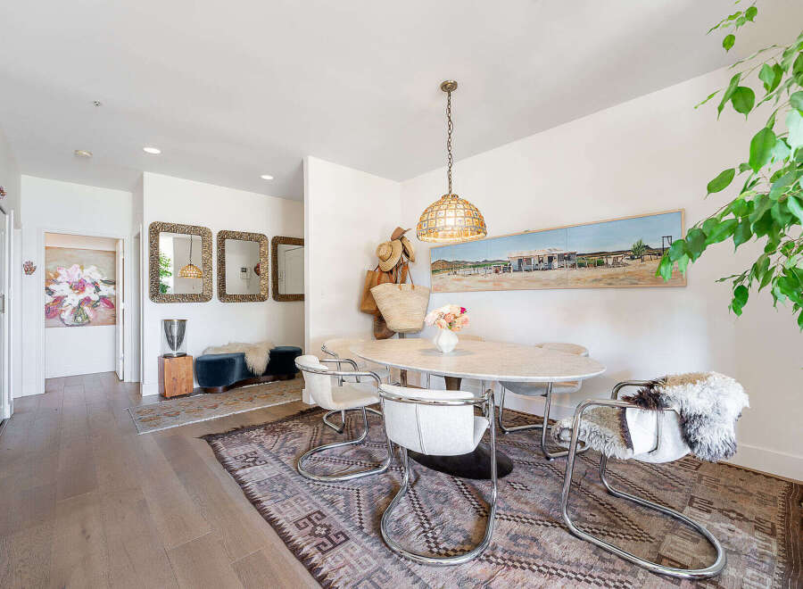 This dining area features a stylish oval marble-top table surrounded by four chrome-frame chairs with white upholstery, perfect for intimate gatherings.