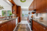 This spacious kitchen features warm cherry wood cabinetry, granite countertops, and a double stainless steel sink.