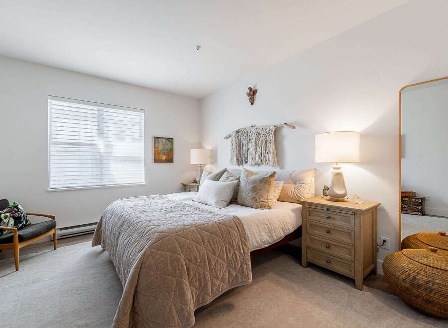Discover this inviting bedroom featuring a plush quilted bedspread and a cozy armchair, perfect for relaxation.