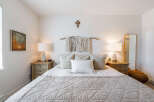 This serene bedroom features a cozy queen-size bed adorned with plush pillows and a textured quilt, creating an inviting atmosphere.