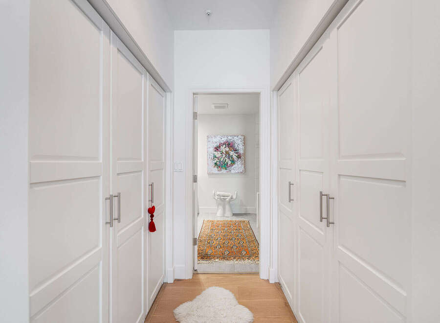 Step into a bright and airy hallway featuring ample storage with floor-to-ceiling white closets on either side.