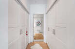 Step into a bright and airy hallway featuring ample storage with floor-to-ceiling white closets on either side.
