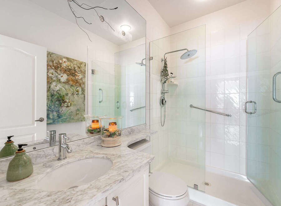 Experience modern luxury in this stunning bathroom featuring a spacious glass-enclosed shower with a rainfall showerhead and a convenient grab bar.