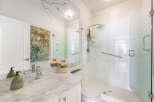 Experience modern luxury in this stunning bathroom featuring a spacious glass-enclosed shower with a rainfall showerhead and a convenient grab bar.