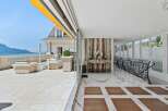 Experience luxurious outdoor living on this expansive terrace, featuring elegant wicker furniture and stunning lake and mountain views.