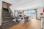 Experience luxurious living with this stunning living room featuring a grand staircase and elegant furnishings.