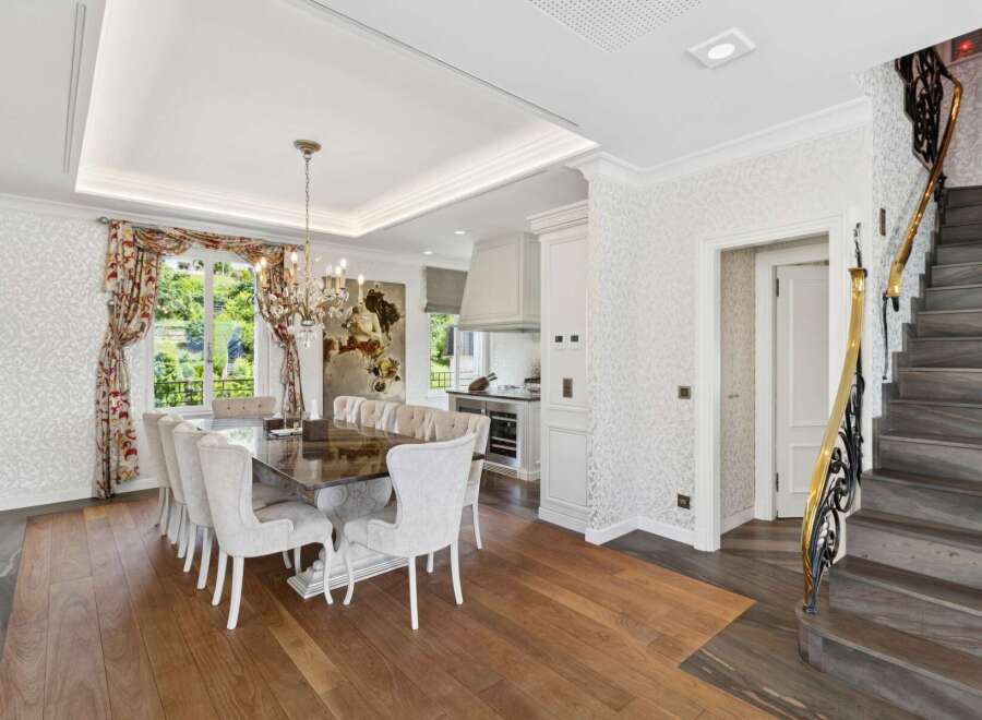 Experience elegant dining in this luxurious home, featuring a spacious dining room with a grand chandelier and seating for ten.