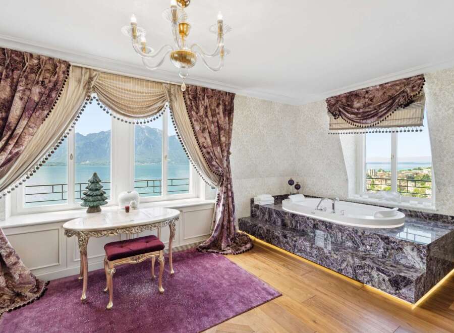Indulge in luxury with this stunning bathroom featuring a deep soaking tub set against a backdrop of breathtaking mountain and lake views.