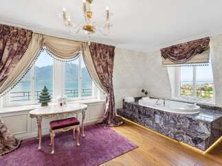 Indulge in luxury with this stunning bathroom featuring a deep soaking tub set against a backdrop of breathtaking mountain and lake views.