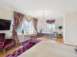 Experience unparalleled luxury in this opulent bedroom featuring a stunning jacuzzi with a marble surround and breathtaking lake views.