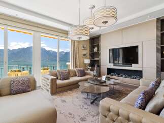 Experience luxury living with breathtaking mountain and lake views from this stunning living room.
