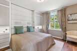 Experience luxury living in this beautifully appointed bedroom, featuring a plush king-sized bed with a striking upholstered headboard and elegant decorative pillows.