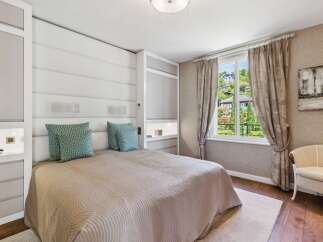 Experience luxury living in this beautifully appointed bedroom, featuring a plush king-sized bed with a striking upholstered headboard and elegant decorative pillows.
