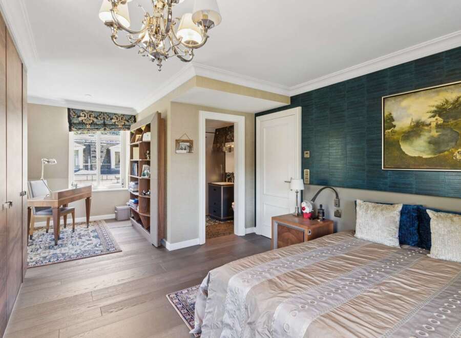 This luxurious bedroom features a comfortable king-size bed with plush pillows and a striking teal textured wallpaper accent wall.