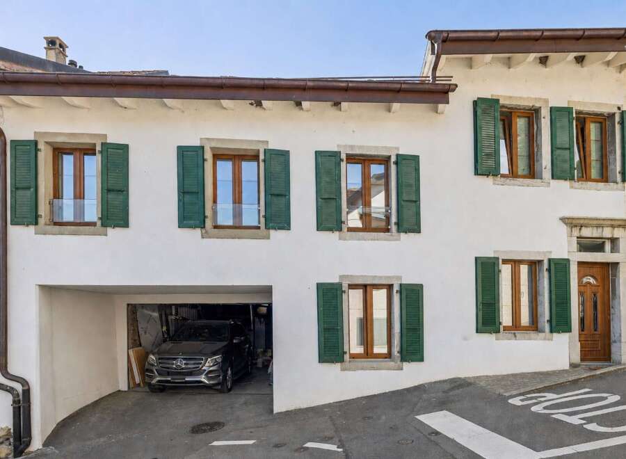 Charming traditional home featuring a spacious garage and multiple windows with classic green shutters.