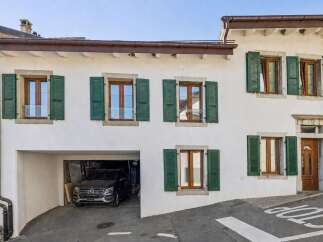 Charming traditional home featuring a spacious garage and multiple windows with classic green shutters.