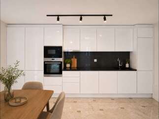 Experience modern living in this sleek kitchen featuring high-gloss white cabinetry and integrated stainless steel appliances, including a microwave and oven.