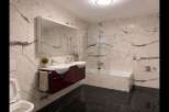 Experience modern luxury in this stunning bathroom featuring elegant marble-patterned walls and sleek black marble floors.
