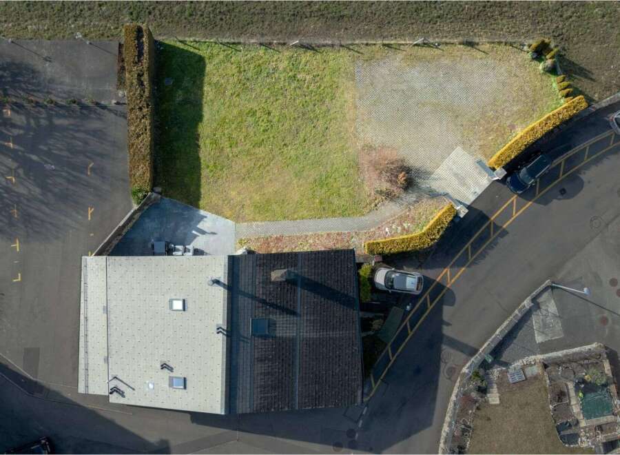 Discover this aerial view showcasing a property with a spacious paved parking area and a well-maintained lawn, perfect for outdoor activities.