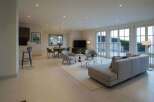 Experience modern living in this spacious open-concept home, featuring a sleek dining area with a large mirror and a comfortable living room with plush seating.