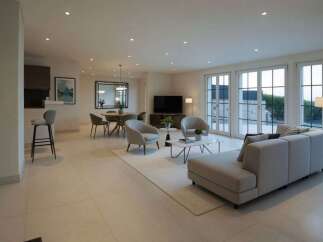 Experience modern living in this spacious open-concept home, featuring a sleek dining area with a large mirror and a comfortable living room with plush seating.
